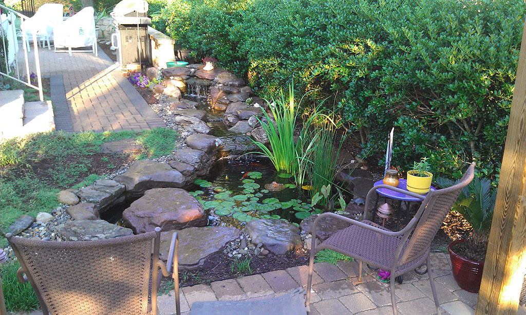Patio by backyard pond Pondscapes Maryland