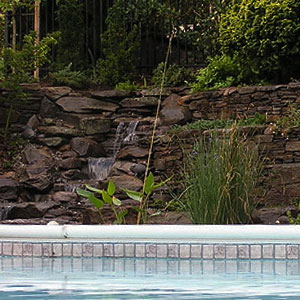Rock wall with waterfall by a pool - Pondscapes Maryland